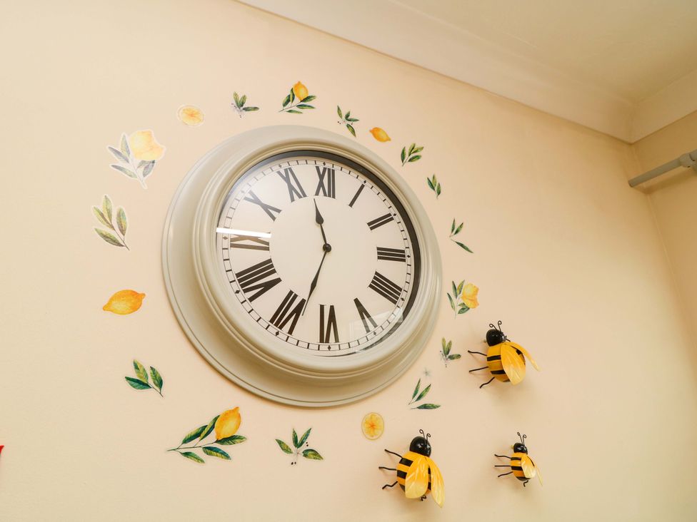 A clock on a wall with decorative bees and lemon illustrations at 5 Overstone Drive in Wisbech