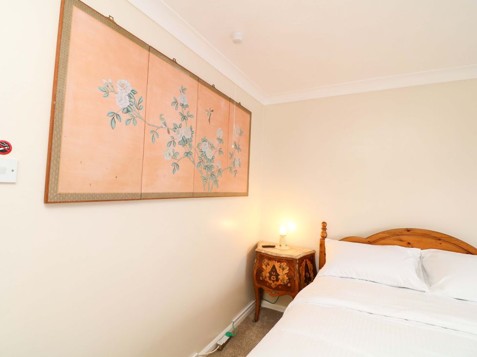 A bedroom with a bed and a nightstand with a lamp at 5 Overstone Drive in Wisbech