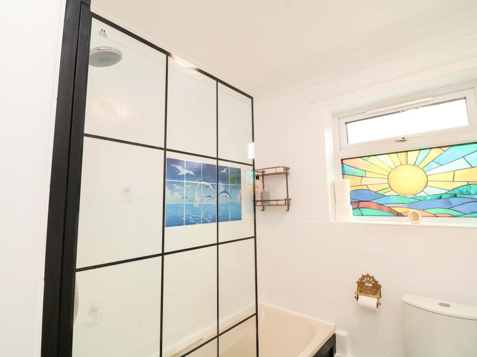 A bathroom with a shower, bathtub and stained glass window at 5 Overstone Drive Wisbech