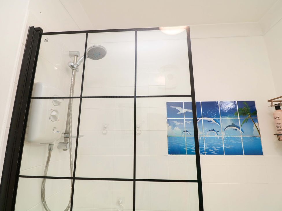A shower with a glass screen and decorative tiles at 5 Overstone Drive in Wisbech