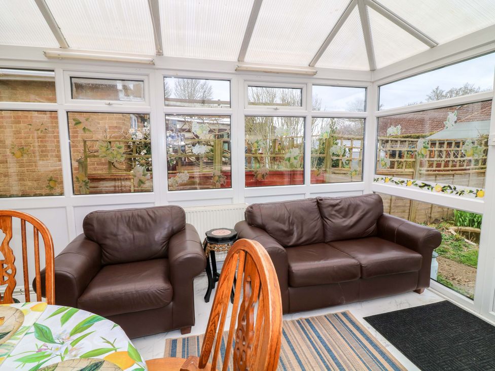 A conservatory with two sofas and a dining table at 5 Overstone Drive Wisbech