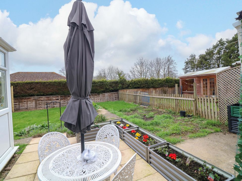 A garden with a table and chairs along with a shed at 5 Overstone Drive, Wisbech