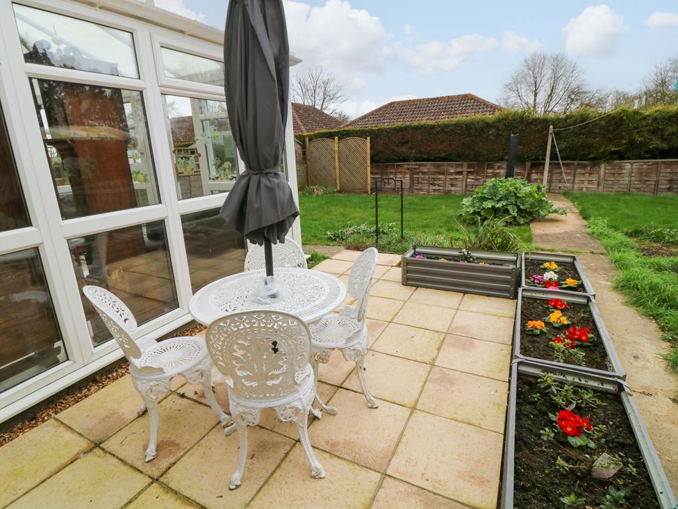 A garden with a table and chairs under an umbrella at 5 Overstone Drive in Wisbech