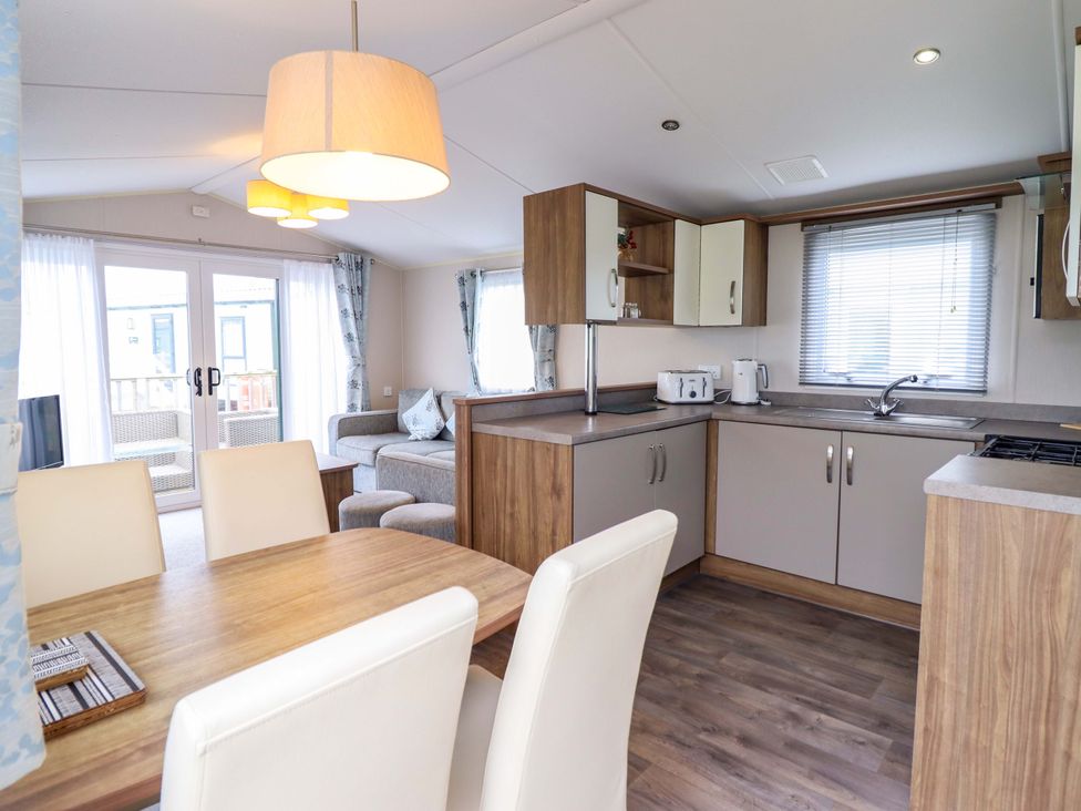 A kitchen and dining area with table and chairs at Sea Breeze C38 Dyffryn Seaside Estate Dyffryn Ardudwy