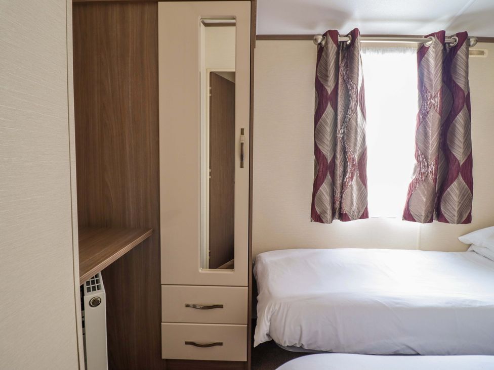 A bedroom with a bed and wardrobe at Beach Retreat E19 Dyffryn Seaside Estate Dyffryn Ardudwy