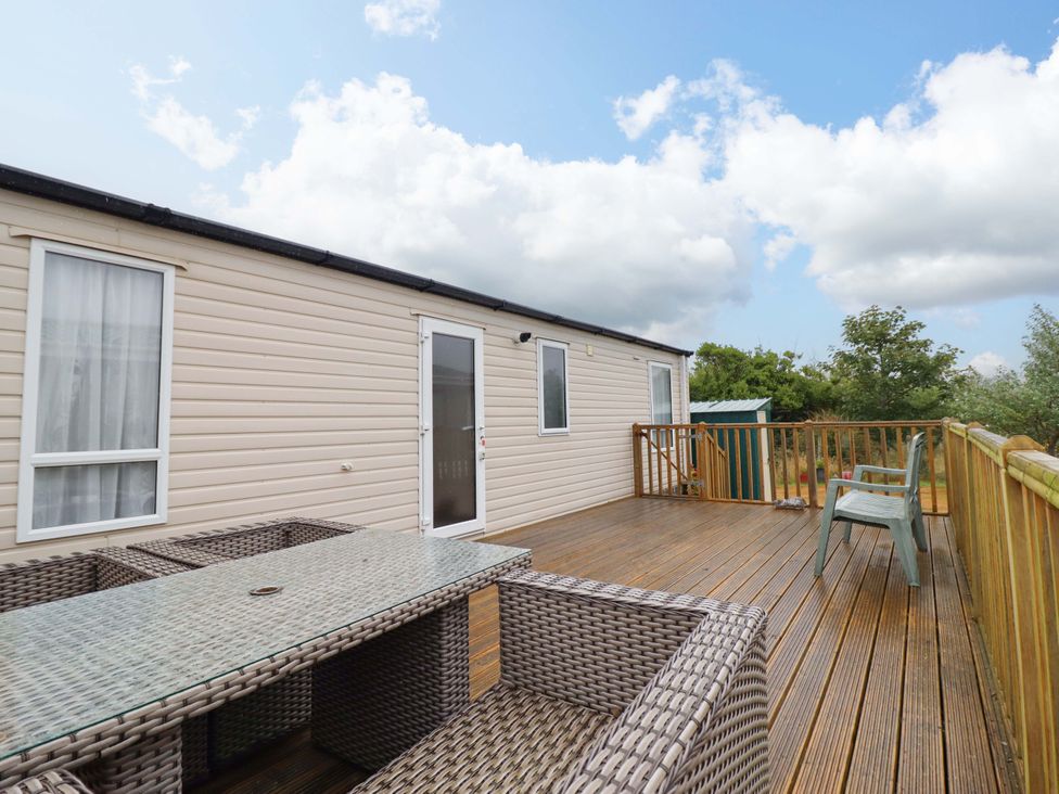 An outdoor space with a wooden deck, table, and chairs at Beach Retreat E19 Dyffryn Seaside Estate Dyffryn Ardudwy