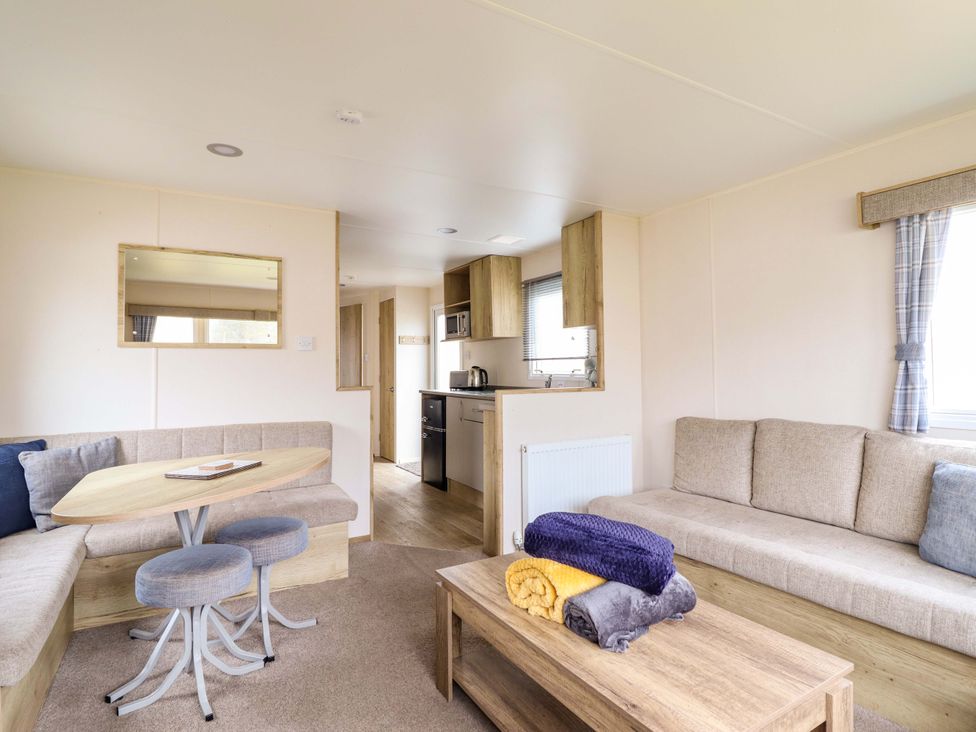 A living room with a sofa and kitchen area at Beachcombers Barmouth Bay Holiday Park in Talybont