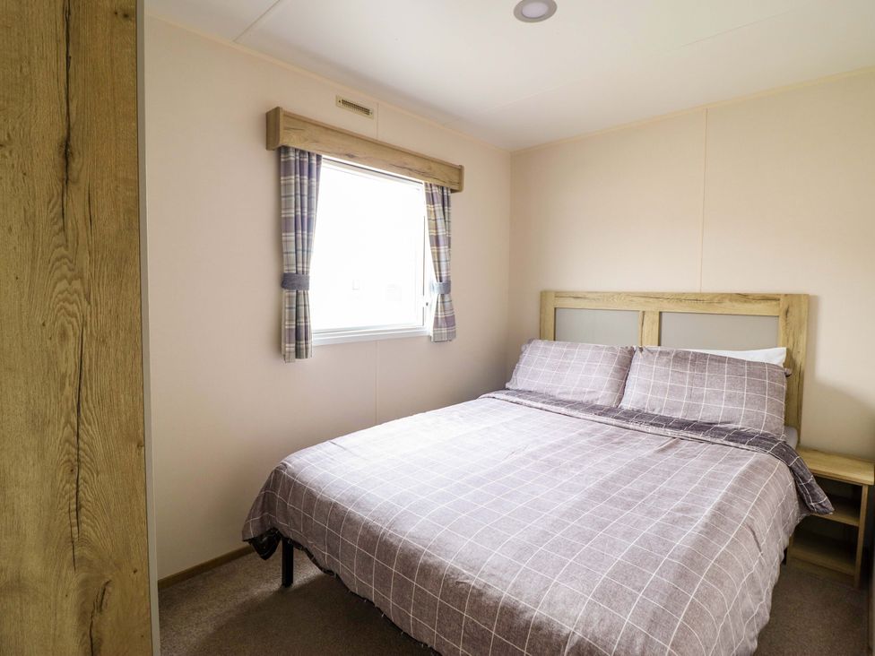 A bedroom with a bed and window at Beachcombers Barmouth Bay Holiday Park, Talybont