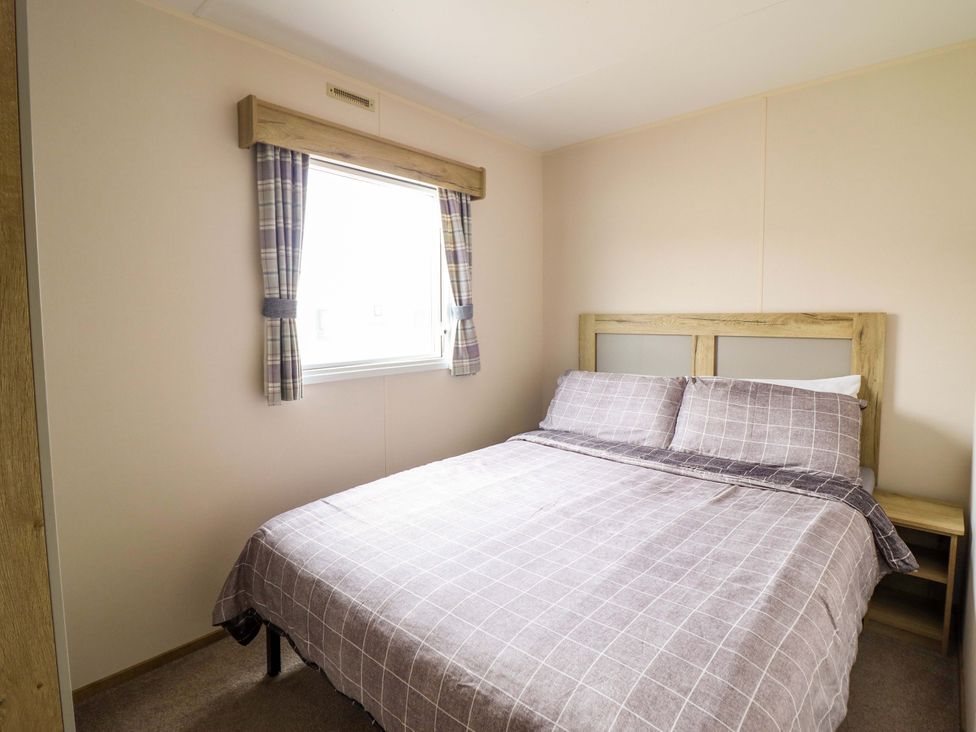 A bedroom with a double bed and window at Beachcombers Barmouth Bay Holiday Park Talybont