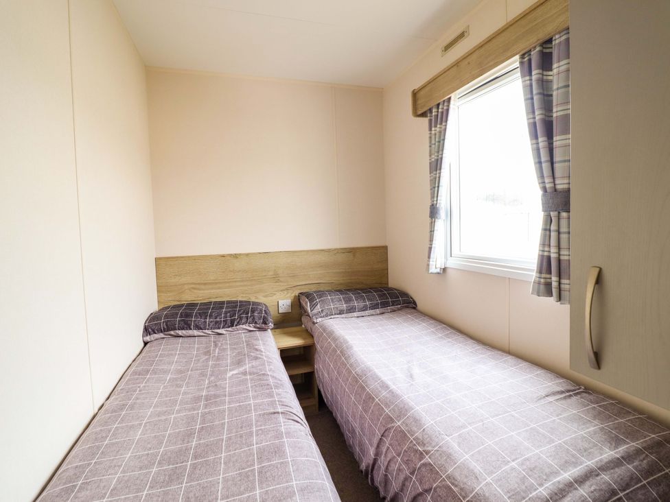 A bedroom with two single beds and a window at Beachcombers Barmouth Bay Holiday Park Talybont