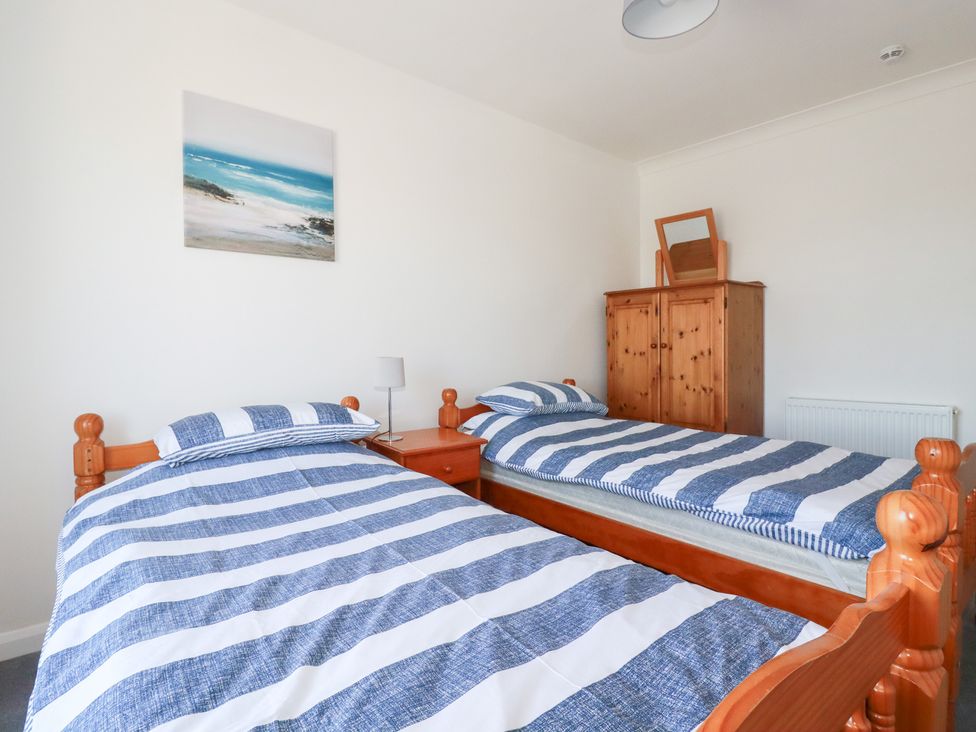 A bedroom with two single beds and a wardrobe at Tregundy Farmhouse Perranporth