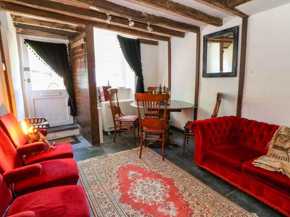 A living room with a dining table and red sofas at The Little Laura Ashley House in Machynlleth