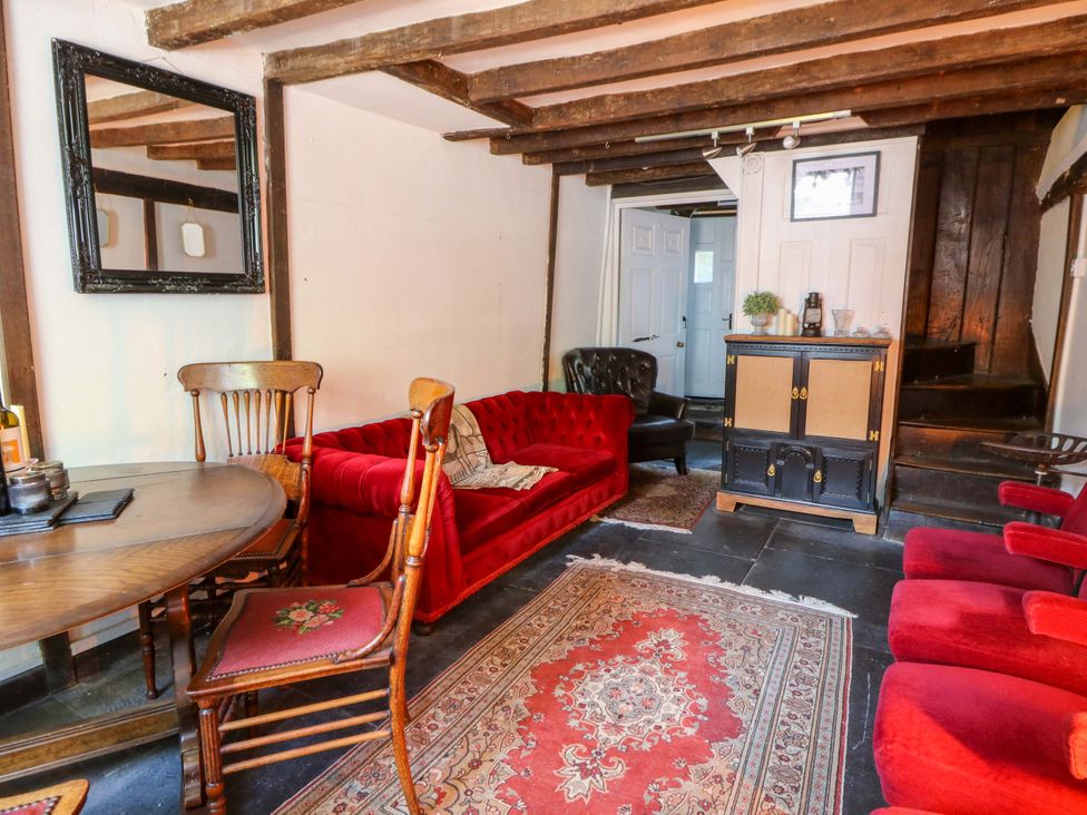 A living room with a red sofa and dining table at The Little Laura Ashley House in Machynlleth