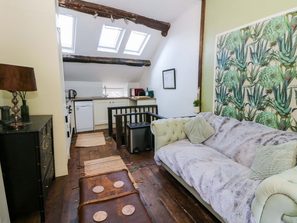 A living room with a sofa and kitchen area at The Little Laura Ashley House in Machynlleth
