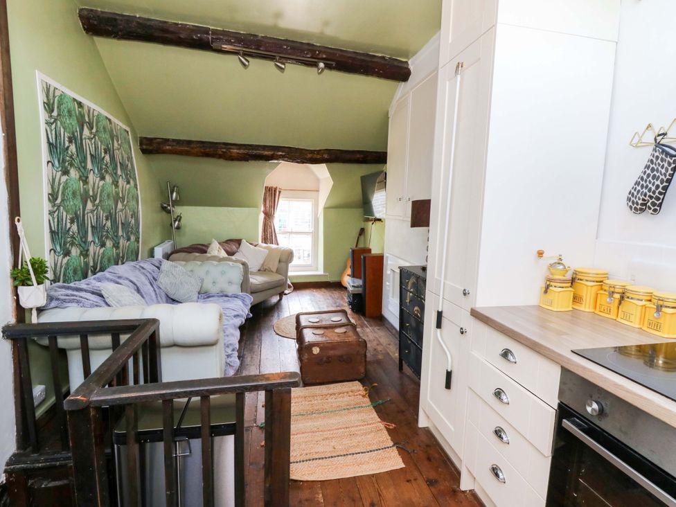 A living room with a sofa and kitchen units at The Little Laura Ashley House Machynlleth