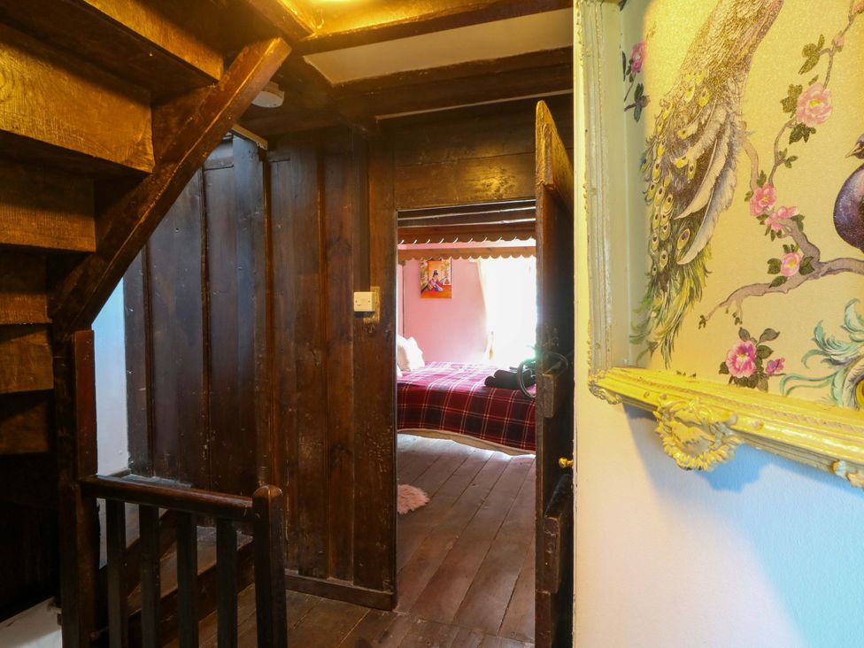 A hallway with a staircase and a doorway leading to a bedroom at The Little Laura Ashley House in Machynlleth