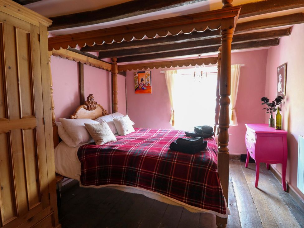 A bedroom with a four-poster bed and a bedside table at The Little Laura Ashley House in Machynlleth
