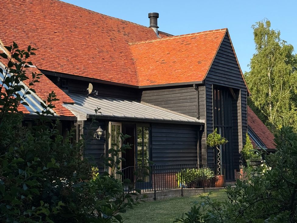 A black wooden house with a red roof and garden at Headland Barn in Maldon