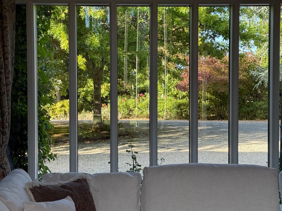 A living room with a view of a garden and gravel driveway at Headland Barn in Maldon