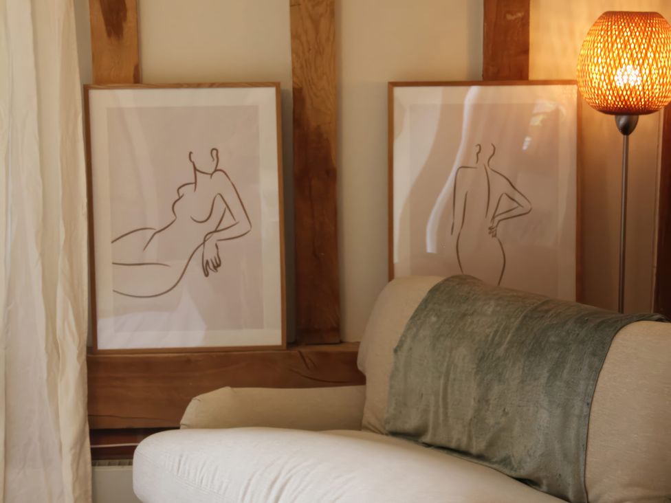 A living room with wall art and a lamp at Headland Barn in Maldon