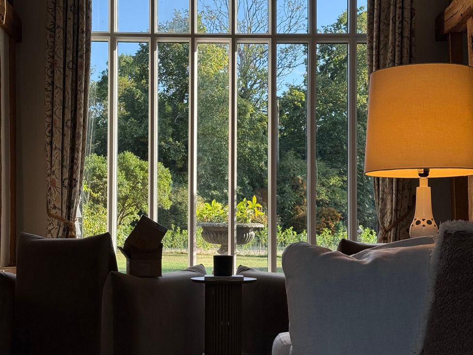 A living room with a window showing garden view at Headland Barn in Maldon