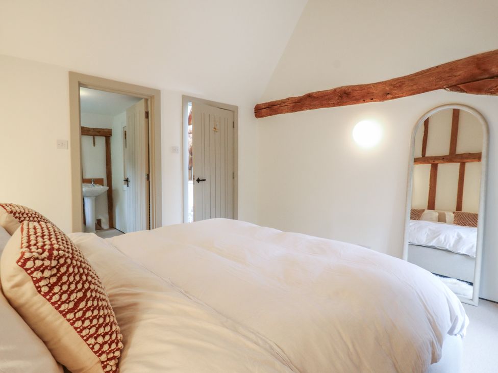 A bedroom with a bed and a mirror at Headland Barn in Maldon