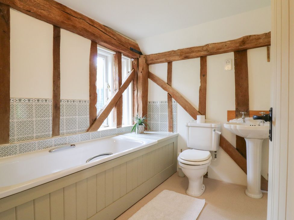 A bathroom with a bathtub, toilet, and sink at Headland Barn in Maldon