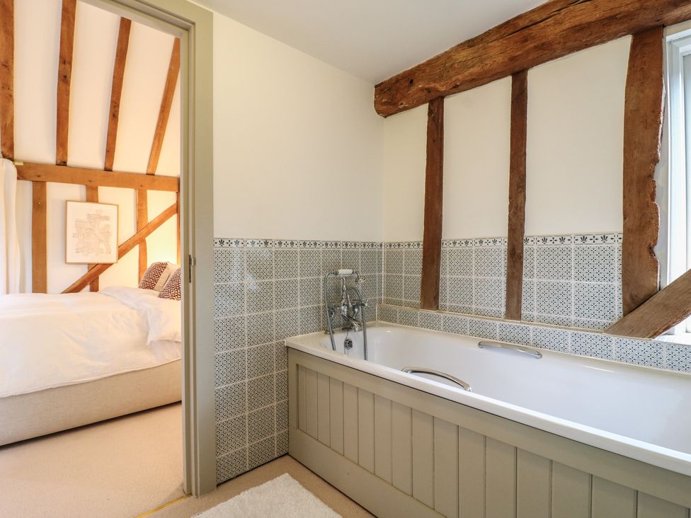 A bathroom with a tub and wall tiles at Headland Barn in Maldon