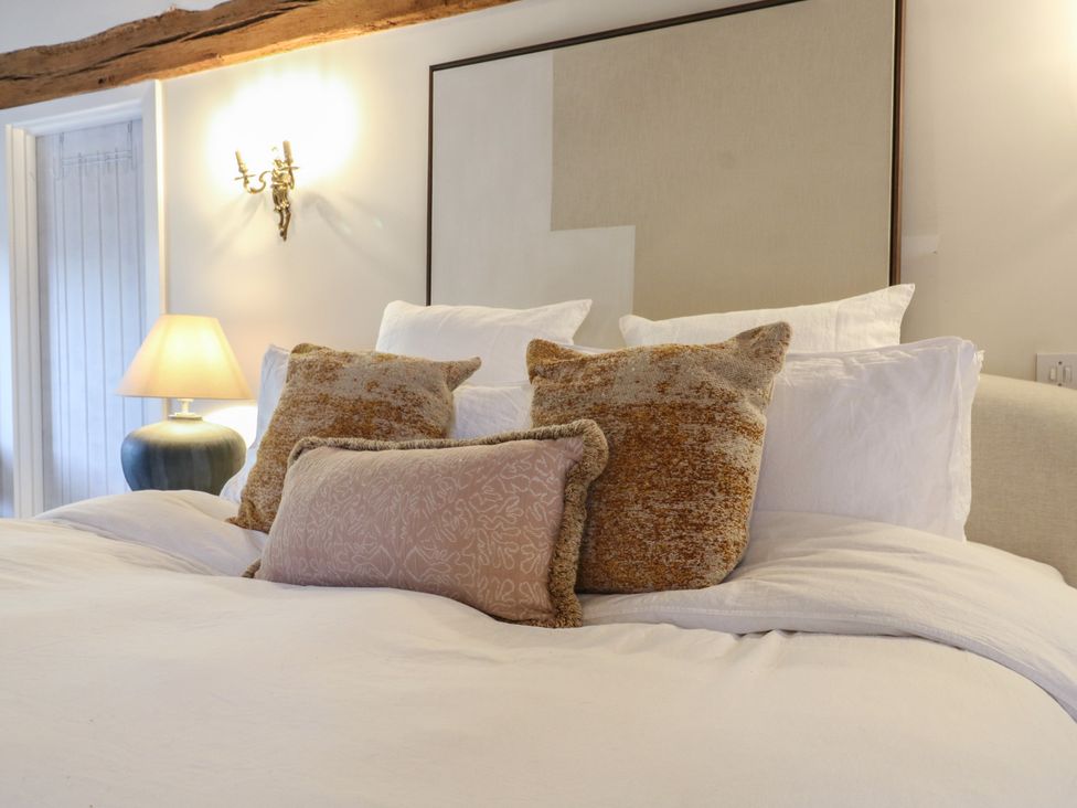 A bedroom with a bed and decorative pillows at Headland Barn in Maldon