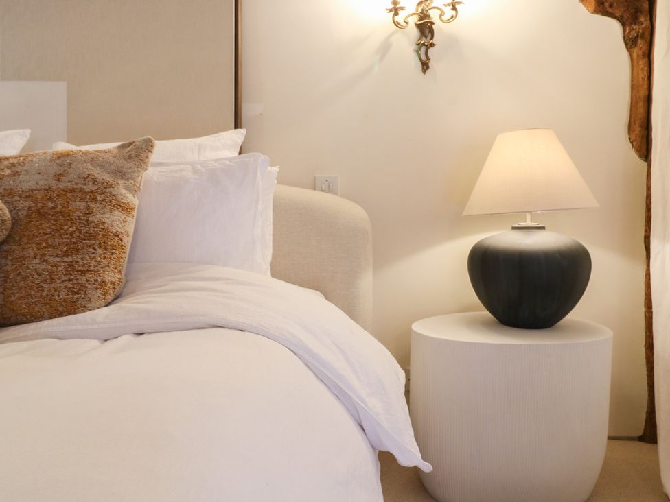 A bedroom with a bed, lamp, and nightstand at Headland Barn in Maldon