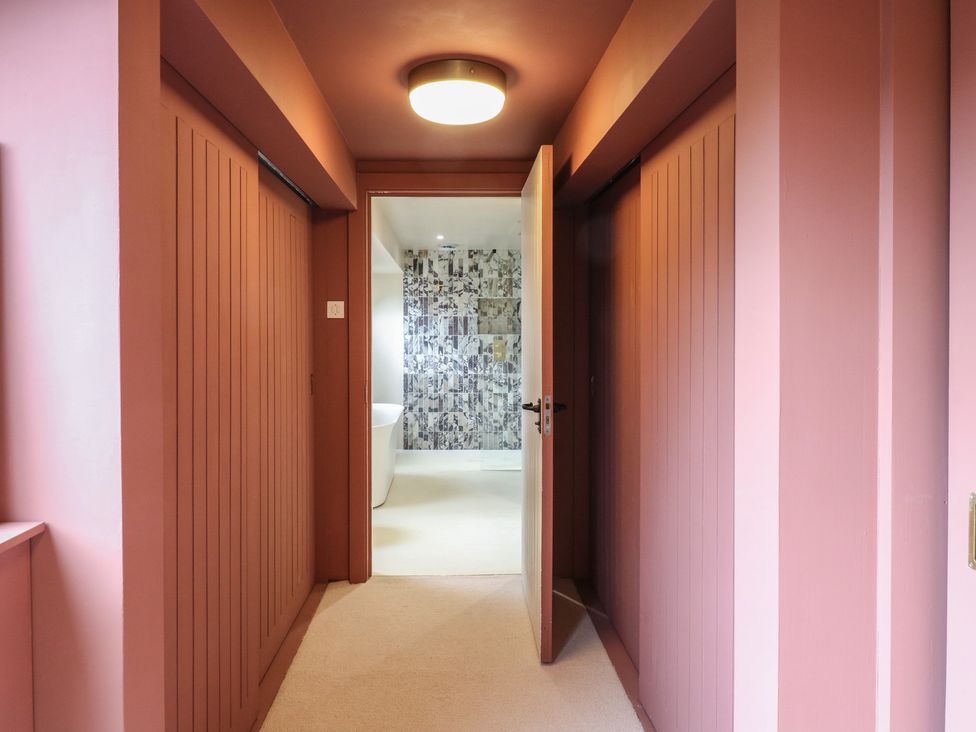 A hallway leading to a bathroom with a bathtub at Headland Barn Maldon