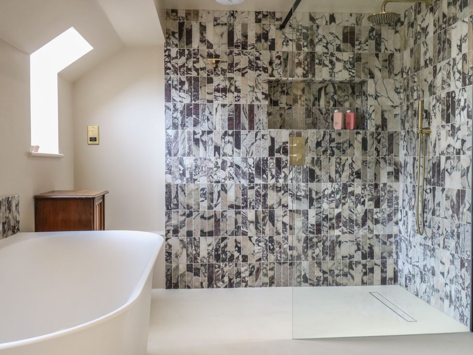 A bathroom with a bathtub and shower area at Headland Barn in Maldon