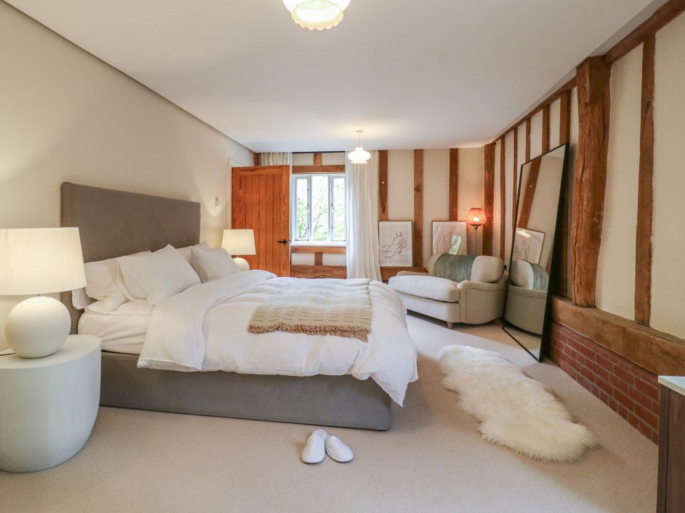 A bedroom with a bed and a sofa at Headland Barn in Maldon