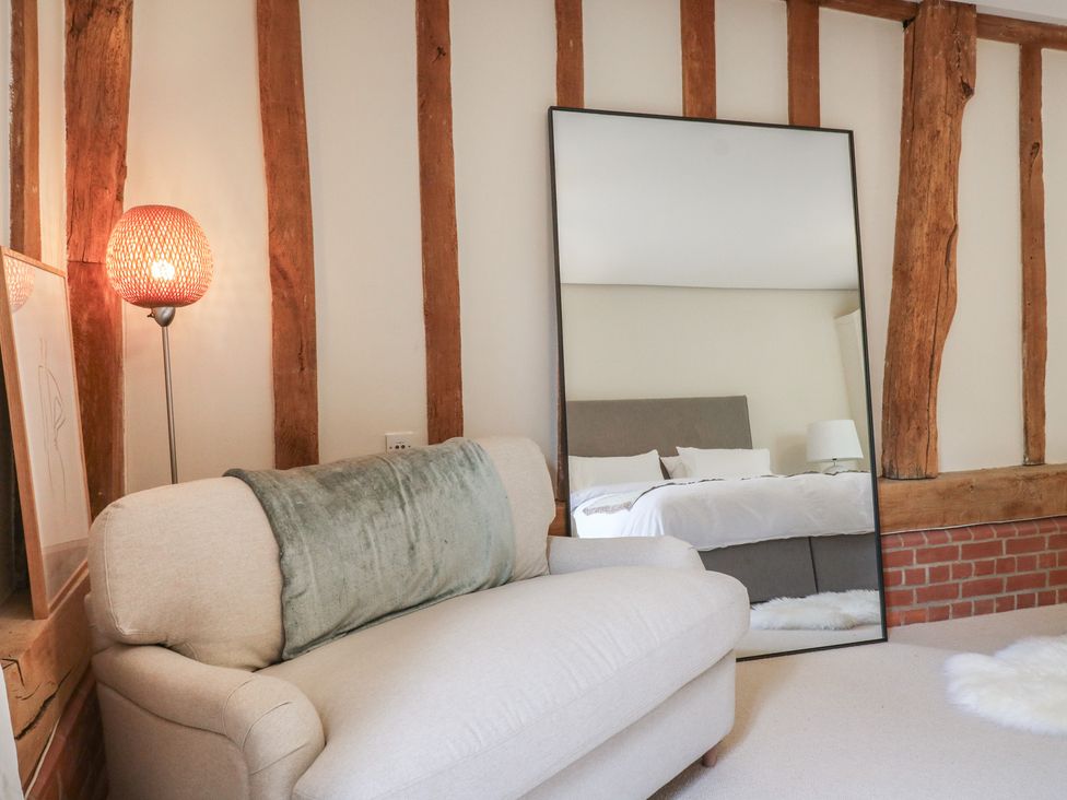 A bedroom with a sofa, lamp, and mirror at Headland Barn in Maldon