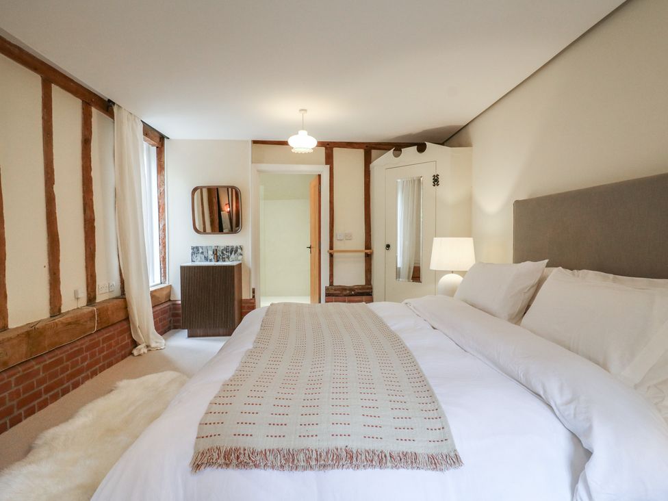 A bedroom with a bed and wardrobe at Headland Barn Maldon