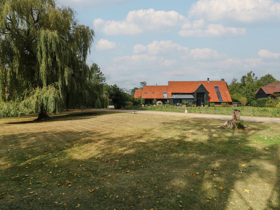 A house with a large lawn and trees at Headland Barn in Maldon