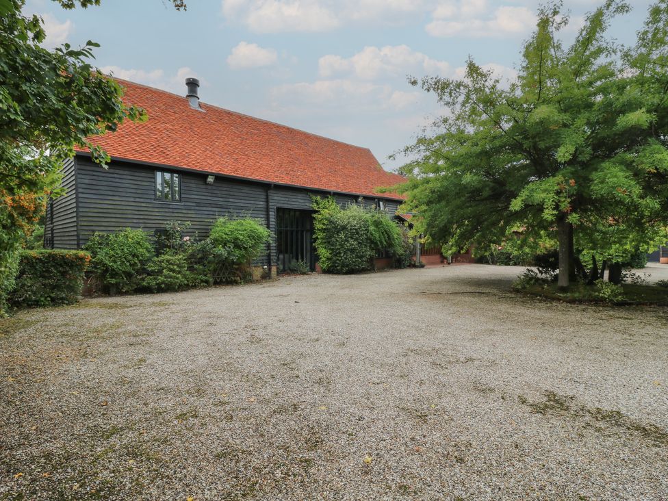 A house with a gravel driveway and trees at Headland Barn in Maldon