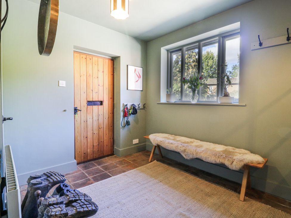 A hallway with a bench and coat hooks at Headland Barn in Maldon