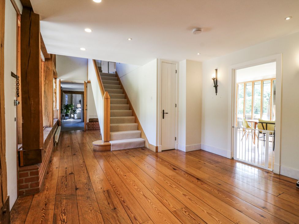 A hallway with a staircase and door at Headland Barn in Maldon