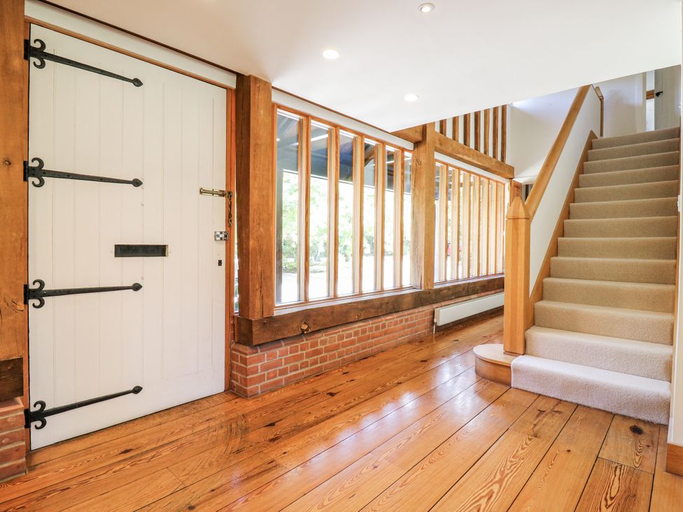 A hallway with a door and staircase at Headland Barn Maldon