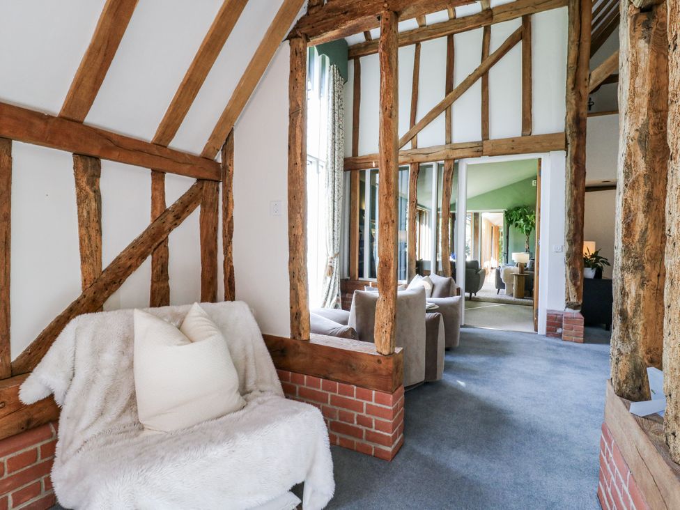 A sitting room with wooden beams and a chair at Headland Barn Maldon