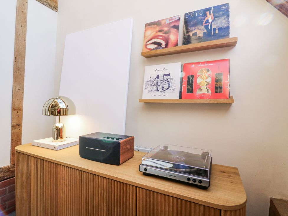 A living room with a shelf displaying vinyl records and a music player at Headland Barn Maldon