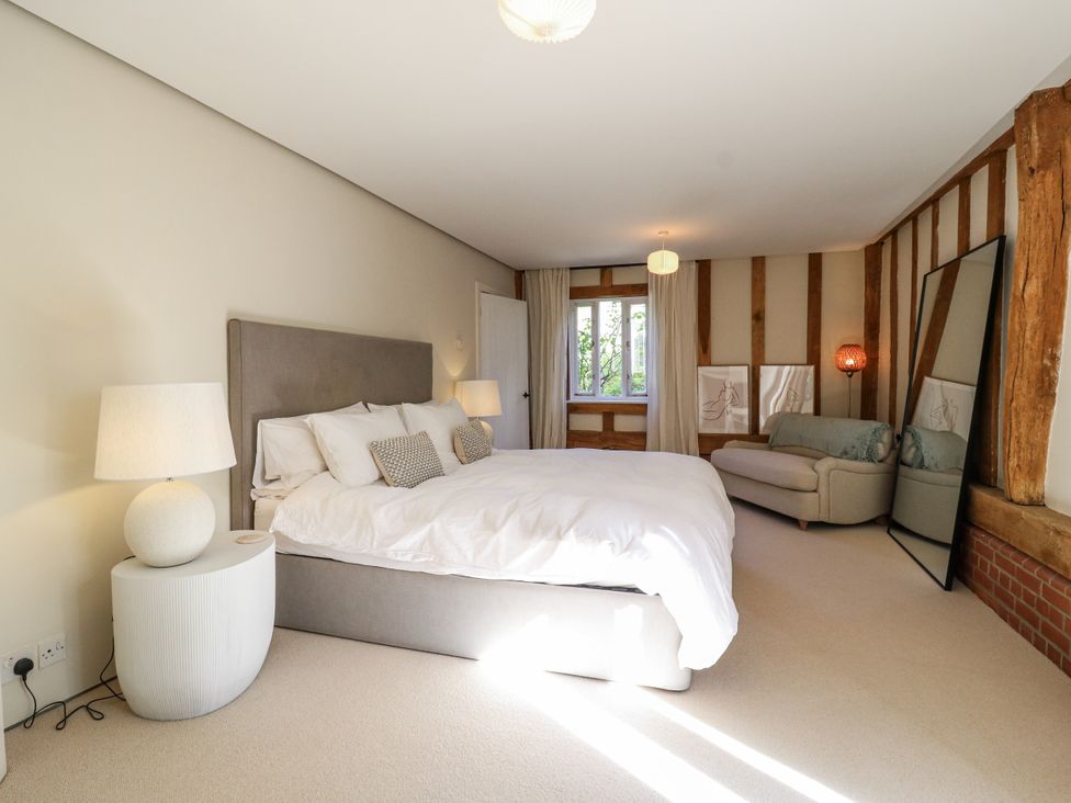 A bedroom with a bed and sofa at Headland Barn Maldon