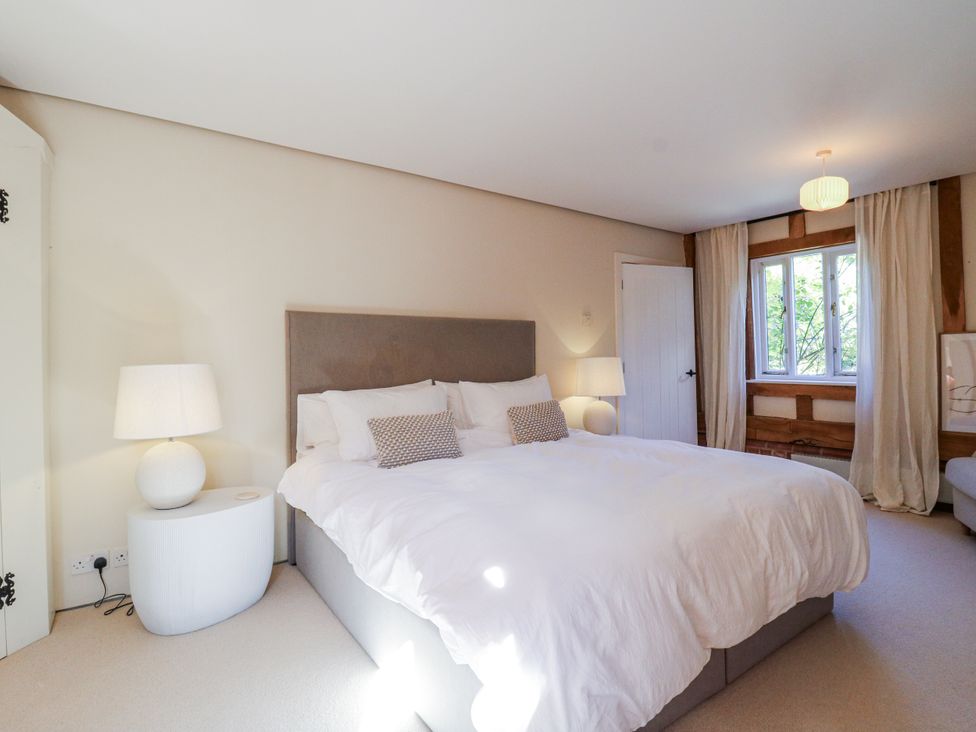 A bedroom with a bed and lamp at Headland Barn in Maldon