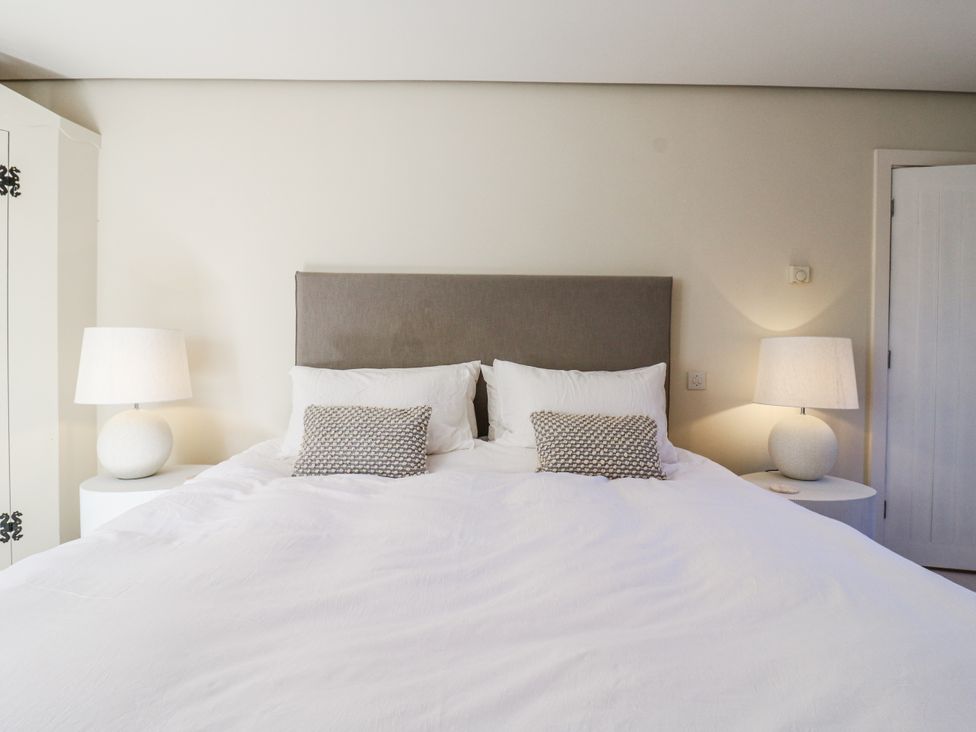 A bedroom with a bed and lamps at Headland Barn in Maldon