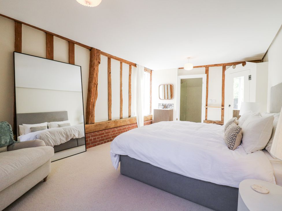 A bedroom with a bed and a mirror at Headland Barn, Maldon