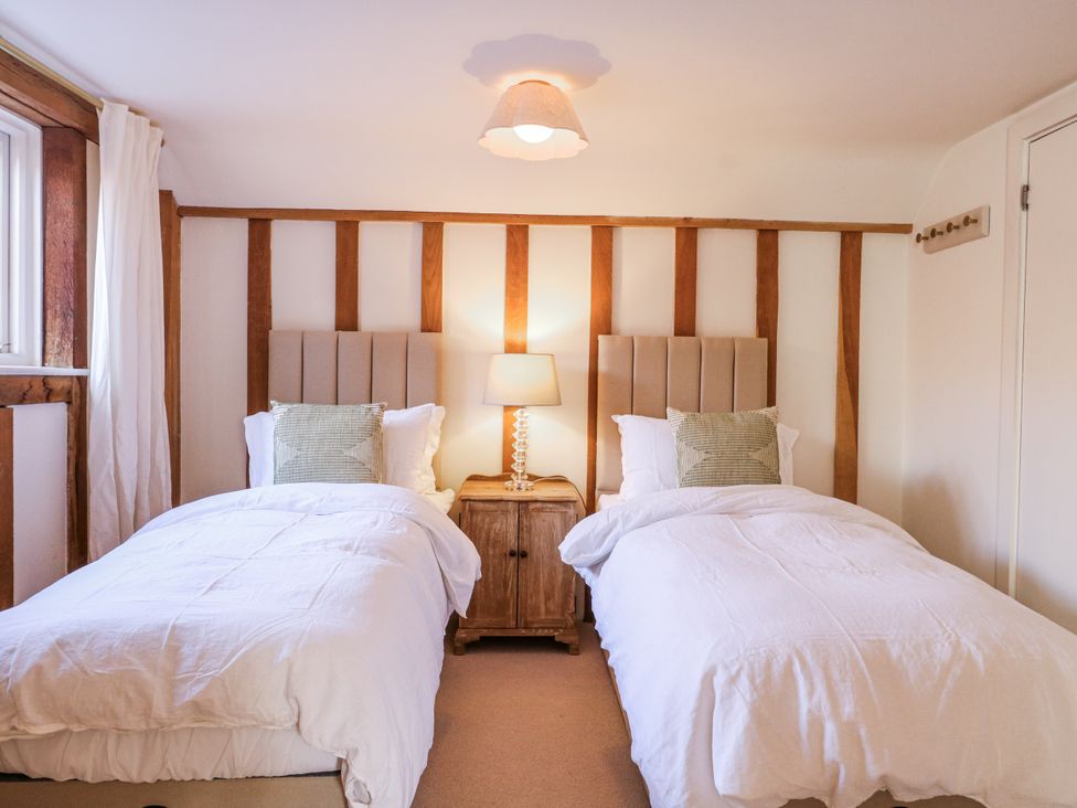 A bedroom with two beds and a lamp at Headland Barn in Maldon