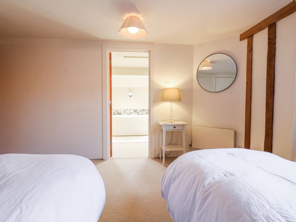 A bedroom with beds and a door leading to a bathroom at Headland Barn Maldon