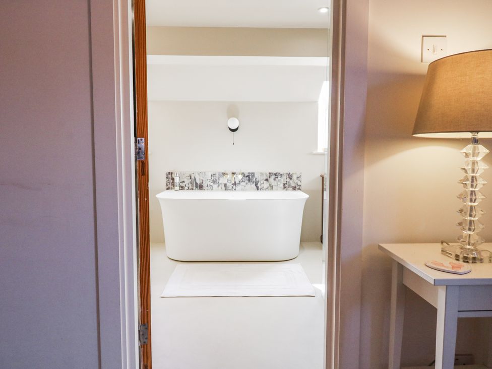 A bathroom with a bathtub and a lamp at Headland Barn in Maldon