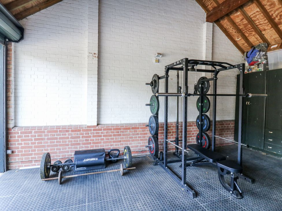 A gym with a power rack and weightlifting equipment at Headland Barn in Maldon